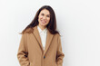 © Tatiana - horizontal photo of a beautiful stylish woman in a beige warm autumn coat on a light background smiling sweetly looking at the camera
