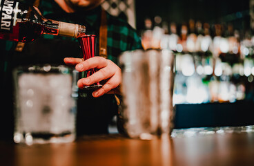 man bartender hand making negroni cocktail. Negroni classic cocktail and gin short drink with sweet vermouth, red bitter liqueur