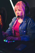 © PoppyPix - Asian girl with bright pink hair wearing a braid and headset focused playing an online team game using professional gaming setup. Vertical shot. High quality photo