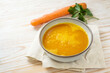 Carrot soup in a bowl on a light wooden table, healthy vegetable meal, recipe by professor Ernst Moro against diarrhea, copy space, selected focus,