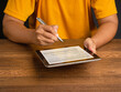 © meeboonstudio - Hand of a man in an orange casual signing on lease contract or agreement on a tablet while sitting at the table
