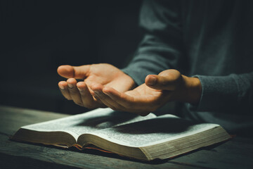 Wall Mural - Hands open palm up in prayer on a Holy Bible in church concept for faith, spirituality, and religion, a woman praying on holy bible in the morning. woman hand with Bible praying. prayer bible