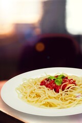 Homemade Italian spaghetti pasta with sauce, tomatoes, basil and parmesan. Traditional cuisine. Served