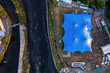 Concert of beer festival area with big blue tent and service areas by a river. Big crowd enjoy all amenities. Aerial top down view. Music event or circus in town. Entertainment industry and business.