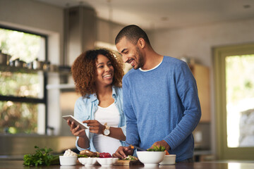 Poster - our food looks just as good as the recipe. shot of a happy young couple using a digital tablet while