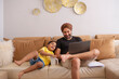 © IndiaPix - Father and daughter watching cartoons on laptop in living room