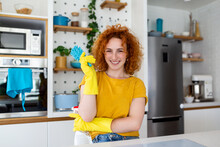 Young Woman Doing House Chores Holding Cleaning Tools. Woman Wearing Rubber Protective Yellow Gloves, Holding Rag And Spray Bottle Detergent. It's Never Too Late To Clean