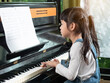 Asian little girl practice play piano in house. Cute kid learning to play piano.