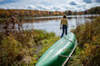 © Elijah Hurwitz - Idyllic scene as young woman approaches tranquil lake upstate New York during peak foliage near canoe