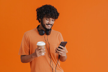 Wall Mural - Young indian smiling man with headphones ,phone and coffee