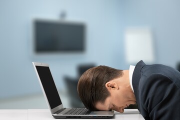 Tired exhausted man, office worker, manager or freelancer, sitting at his desk, tired of working in a laptop, overworked, having a headache,