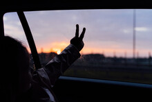 Crop Child Doing Peace Gesture On Car Window During Trip
