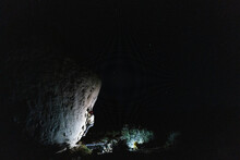 Night Shot Of Solitary Rock Climber In Headlamp On Large Boulder