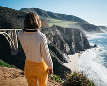 A Well Dressed Young Woman In A Sweater Takes In The Stunning Views At Bixby Bridge In Big Sur, CA 