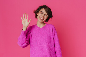 White young woman wearing sweater smiling and waving hand