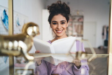 Radiant brunette woman with beautiful appearance holds diary in hands. Positive female student with notebook organizer Gentle sweet girl in purple sweater posing at camera smiling sincerely from.