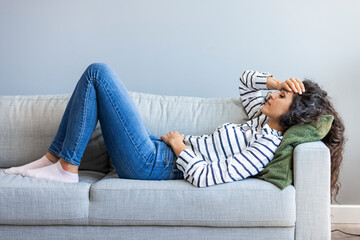 Full length young woman lying on sofa suffers from heartache cover face with hands crying feels desperate unhappy unwell having mental pain or serious health problems, beak up divorce abortion concept