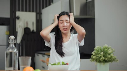 Wall Mural - Unhappy female looking to organic greens vegetable salad in weight loss diet and wellness on table. Tired woman dislike eat bored with food healthy salad breakfast in kitchen. Diet food concept.