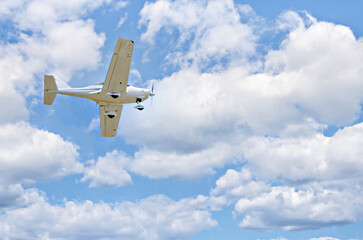 Wall Mural - Single engine ultralight plane flying in the blue sky with white clouds