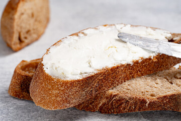 Spreading white cheese on bread