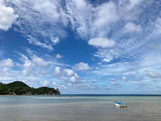 Small rowing boat floating in the sea and blue sky background.