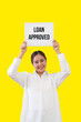 © littlestocker - Asian woman holding loan approved board on yellow background. Business finance concept