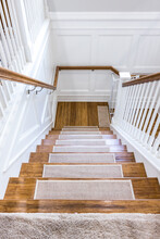 Wood Stairs With Carpet Rug Accents For Grip With A White Painted Handrail In A New Construction House