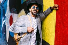 Stylish Hispanic Man Leaning On Graffiti Wall