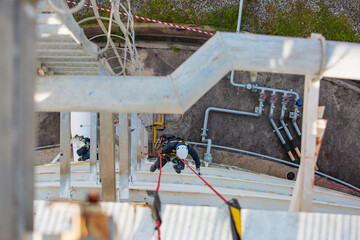 Top view male worker inspection wearing safety first harness rope safety line working at a high place on tank roof spherical