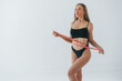 With measuring tape. Woman in underwear with slim body type is posing in the studio