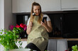 Puzzled and concentrated plump, plus size blond woman with ladle sit on kitchen drawer use smartphone. Organic eco food