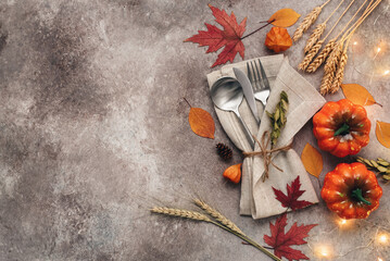 Autumn table setting place with cutlery and pumpkins, brown grunge background. Thanksgiving and halloween concept. Top view, flat lay.