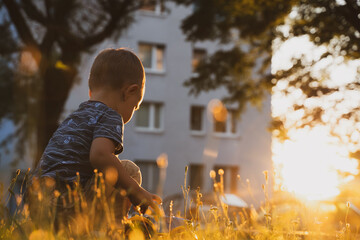 Wall Mural - Child playing with toys outside. Little boy having fun on playground in sunset. Outdoor creative activities for kids. Summer and childhood concept