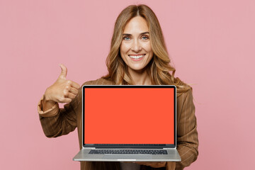 Young employee business woman 30s she in casual brown classic jacket hold use work on laptop pc computer with blank screen workspace area show thumb up isolated on plain pastel light pink background