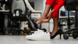 © Михаил Решетников - African woman changing from high heels to sneakers in the office. Tired legs.