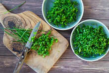 Fresh And Chopped Spicy Parsley And Chives Herbs On Cutting Board, Top View.