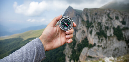 Wall Mural - A male is looking for a compass in the mountains