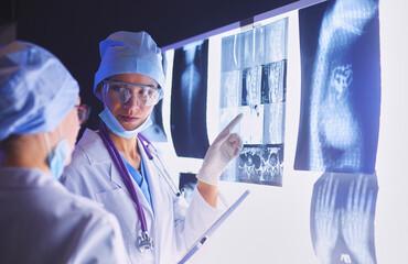 Wall Mural - Two female women medical doctors looking at x-rays in a hospital.