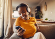 Young woman texting, browsing and scrolling social media on a phone feeling happy, carefree and smiling. Listening to music, podcast or watching funny internet memes online while relaxing on a sofa