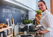 © lenets_tan - Young woman standing by the stove in the kitchen