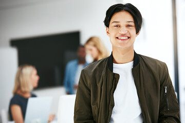 Wall Mural - Happy, confident and carefree business man relaxing in a modern office with colleagues in the background. Portrait of a young proud professional smiling, taking a break to rest at work