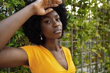 Portrait of a beautiful young african american woman posing against backdrop of green hedge