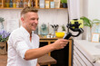 Blond laughing guy filming a video blog on a mobile device using an electronic image stabilizer in the kitchen