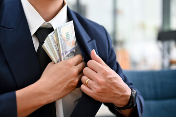 Wall Mural - A businessman take a dollar money banknote into his suit pocket. cropped