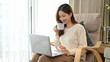 © bongkarn - Beautiful Asian female or businesswoman working from home, sipping coffee and using a laptop