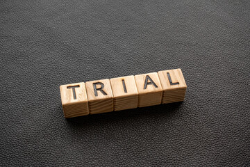 Poster - Trial - word from wooden blocks with letters, trial, test, pilot concept, black leather background