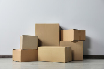 Many closed cardboard boxes on floor near white wall. Delivery service