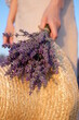 woman holding a bouquet of lavender and a straw hat in a field at sunset