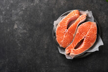 Salmon. Raw Salmon Steak. Fresh Raw Salmon Fish With Cooking Ingredients, Herbs And Lemon Prepared For Grilled Baking On Black Background. Healthy Food. Top View. Copy Space.