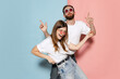 Young stylish happy man and excited girl dancing hip-hop at studio on blue and pink trendy color background. Emotions, youth, love and active lifestyle concept
